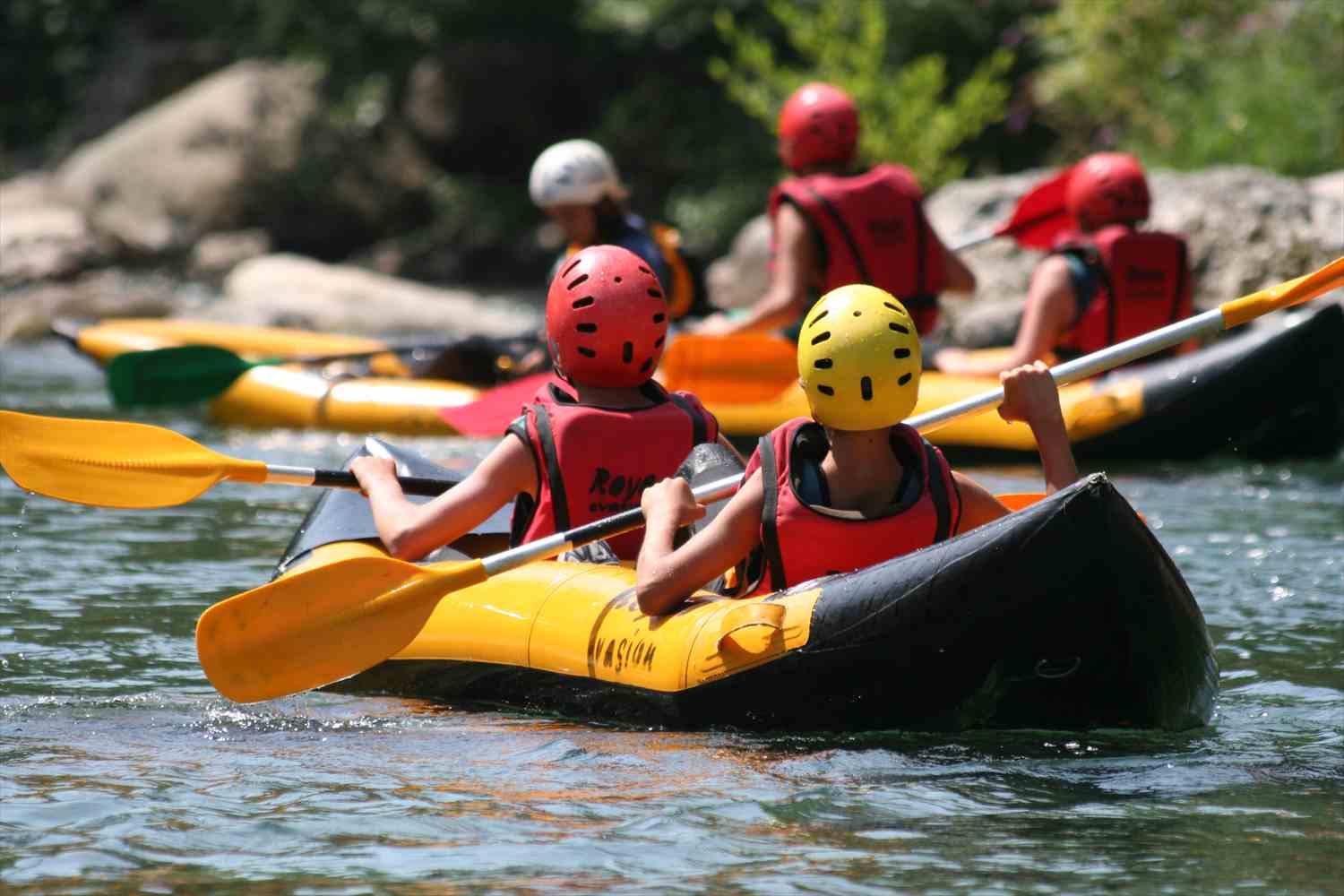 Children paddling canoes together on a river