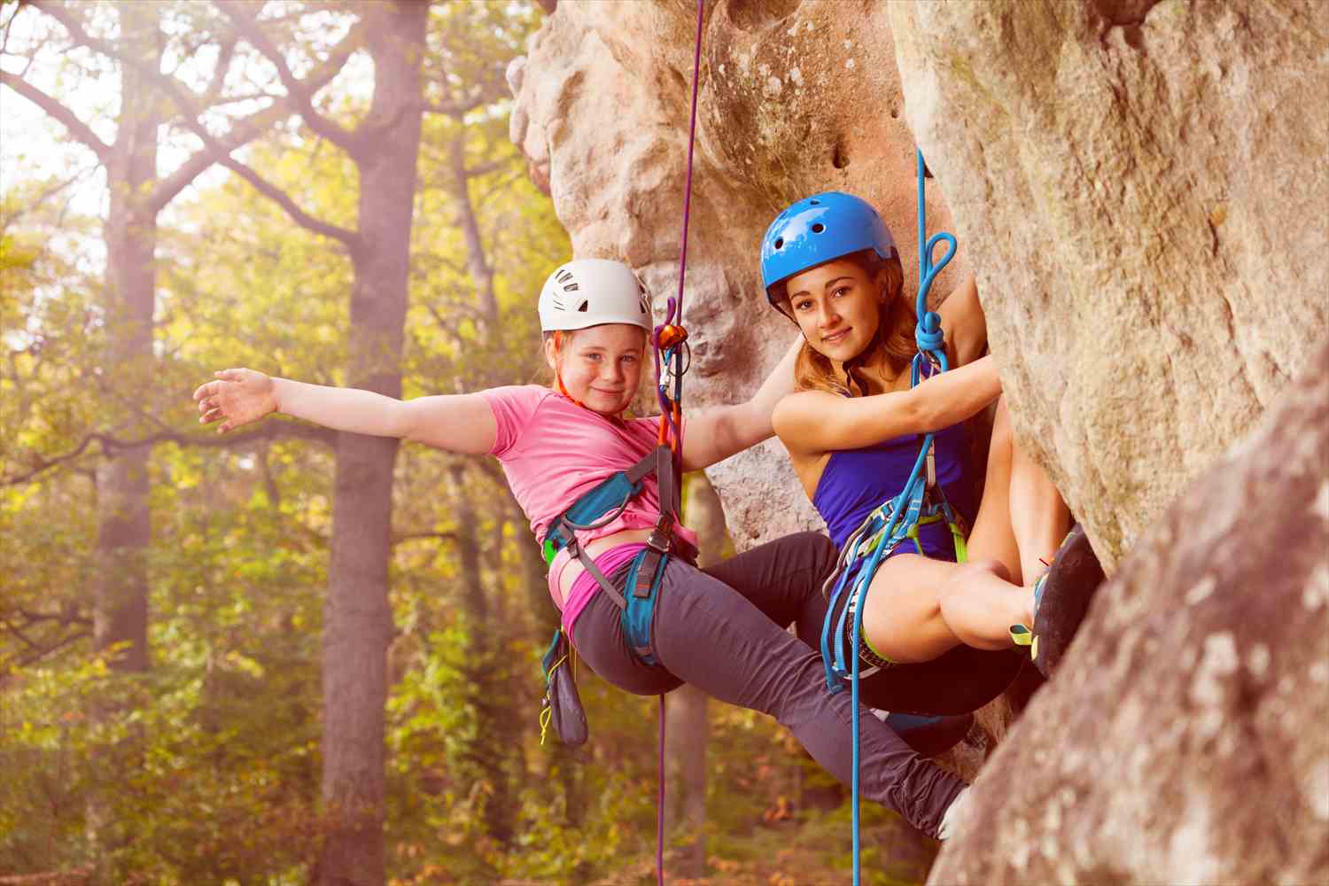 Friends supporting one another while rock climbing outdoors