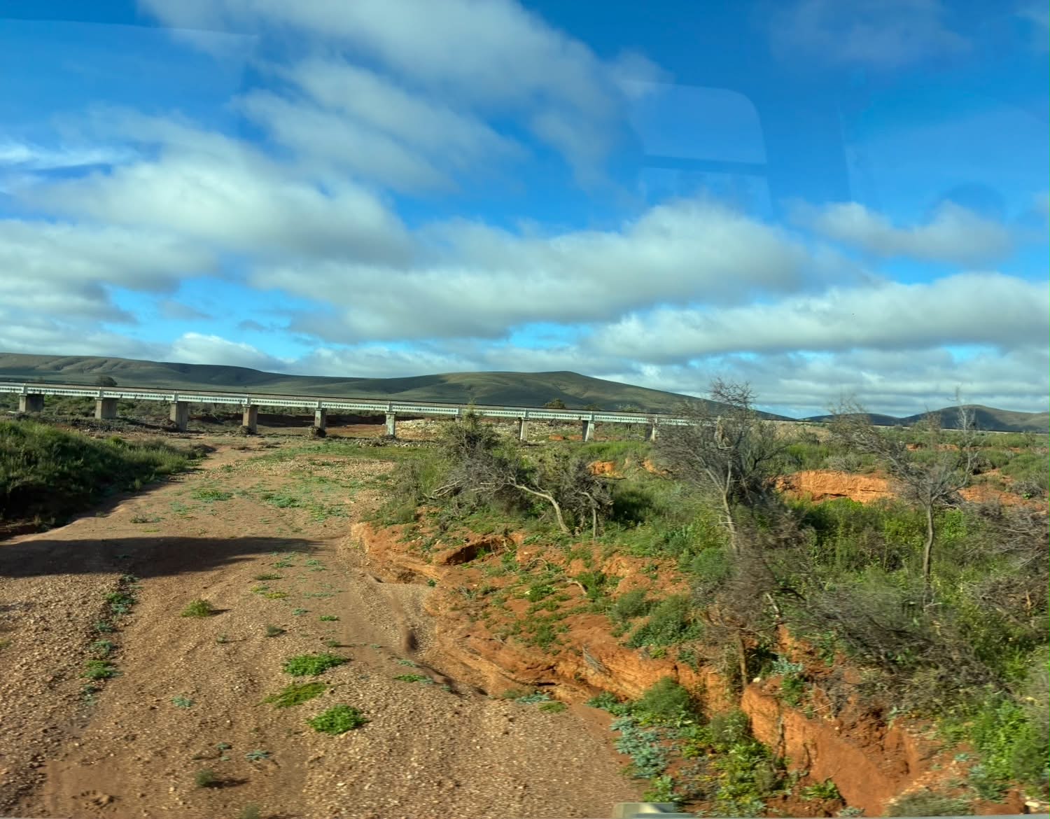 Bridge and red earth landscape seen from the Uluru expedition convoy