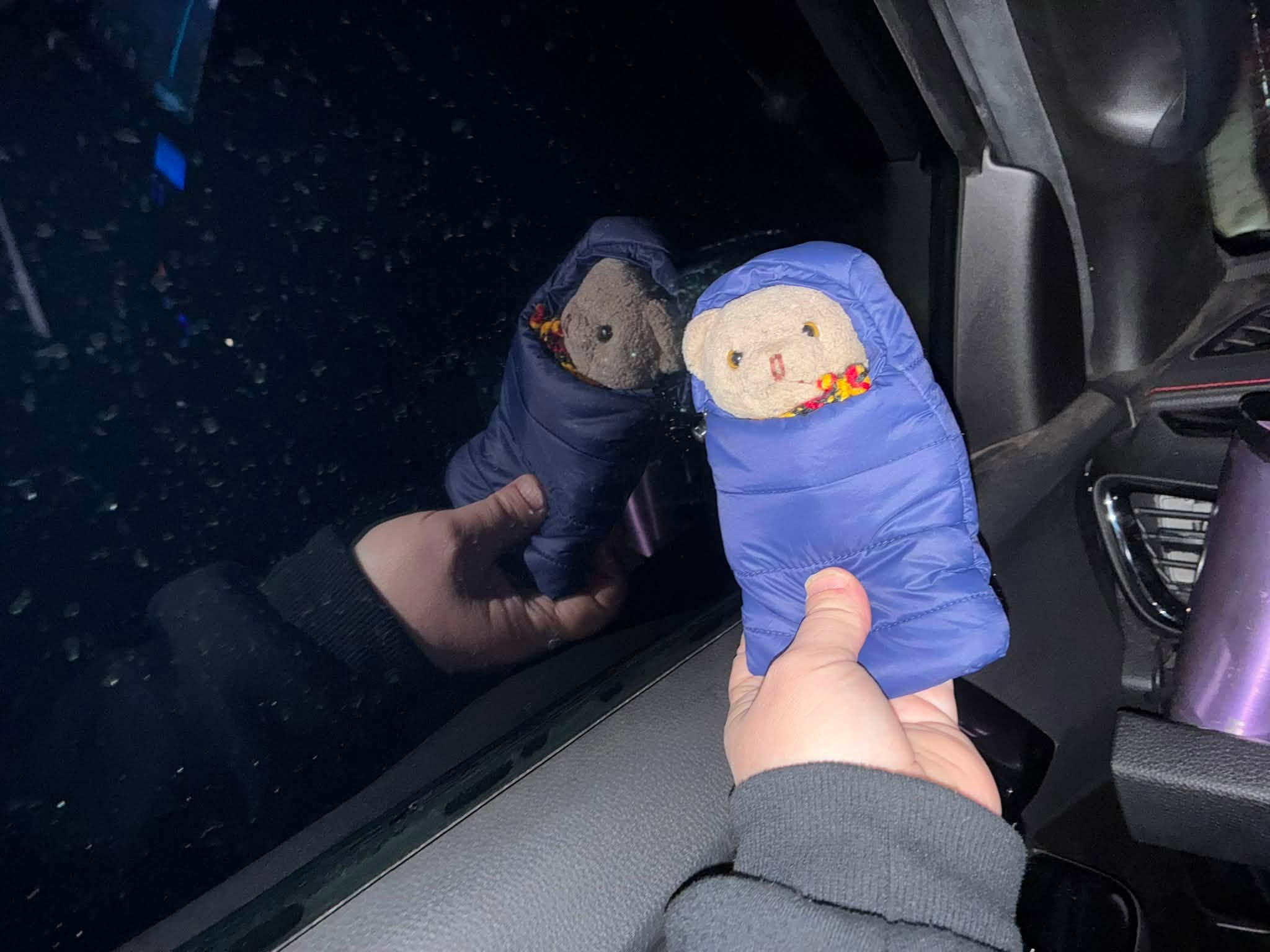 Two Uluru expedition mascots wrapped in miniature sleeping bags during the cold journey home