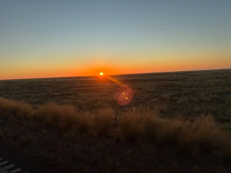 Sunrise over the flat outback landscape during the Uluru expedition journey home