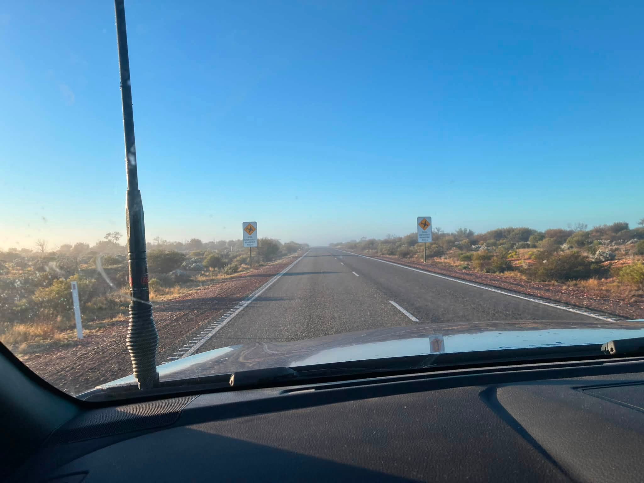 Open highway through red dirt and scrub on the Uluru expedition journey from Coober Pedy to Gawler