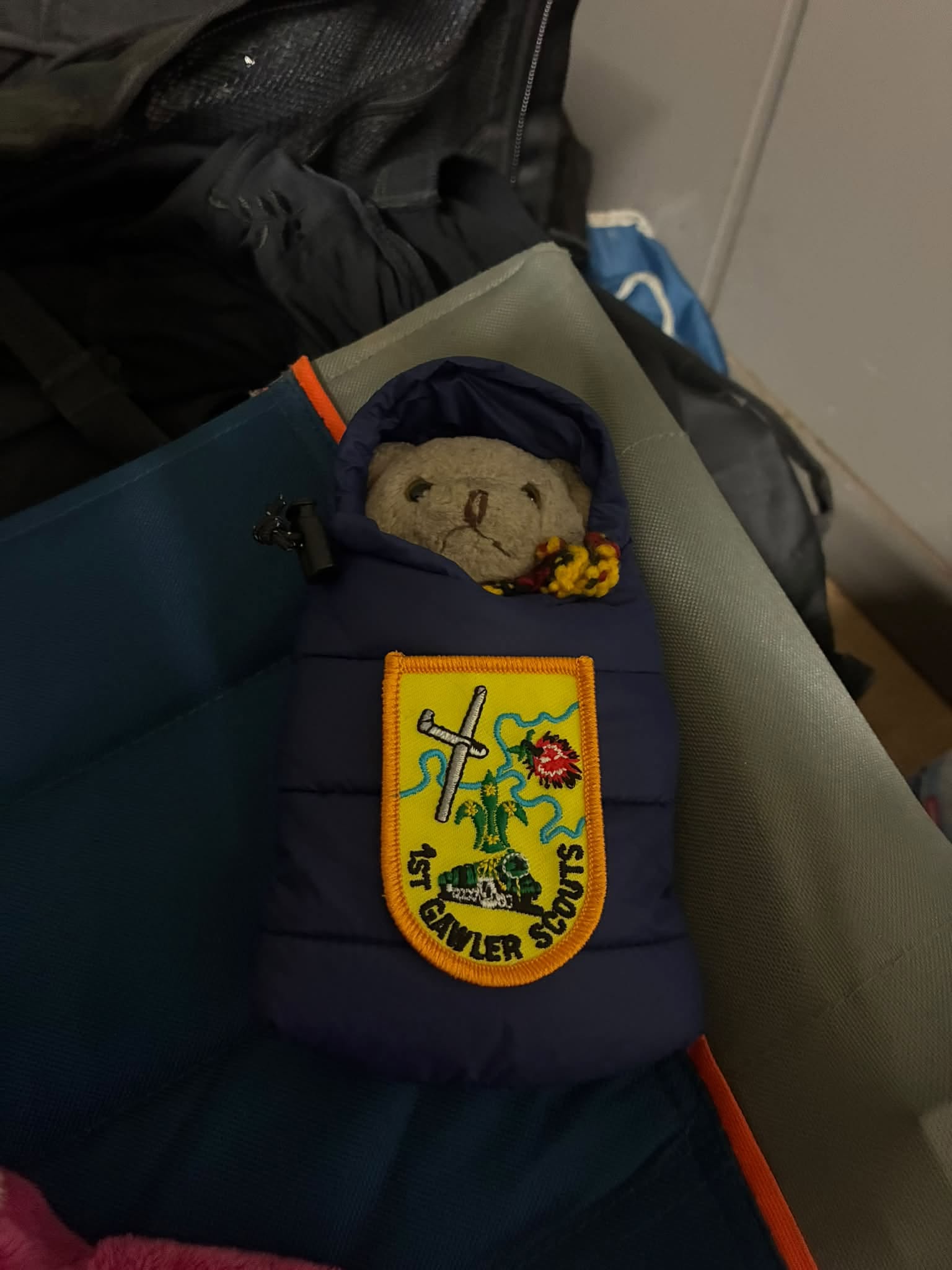 Gilbert, the Uluru expedition mascot, tucked into a miniature sleeping bag with a 1st Eltham Scouts badge